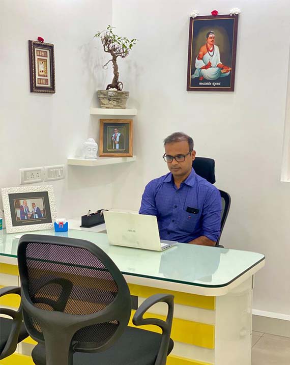 Dentist near me in blue shirt working on laptop